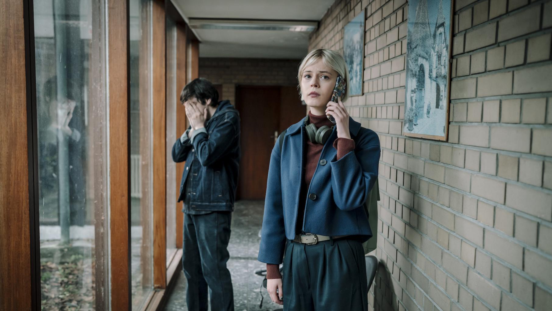 Patience stands on the phone while Billy stands behind her with his hands on his face